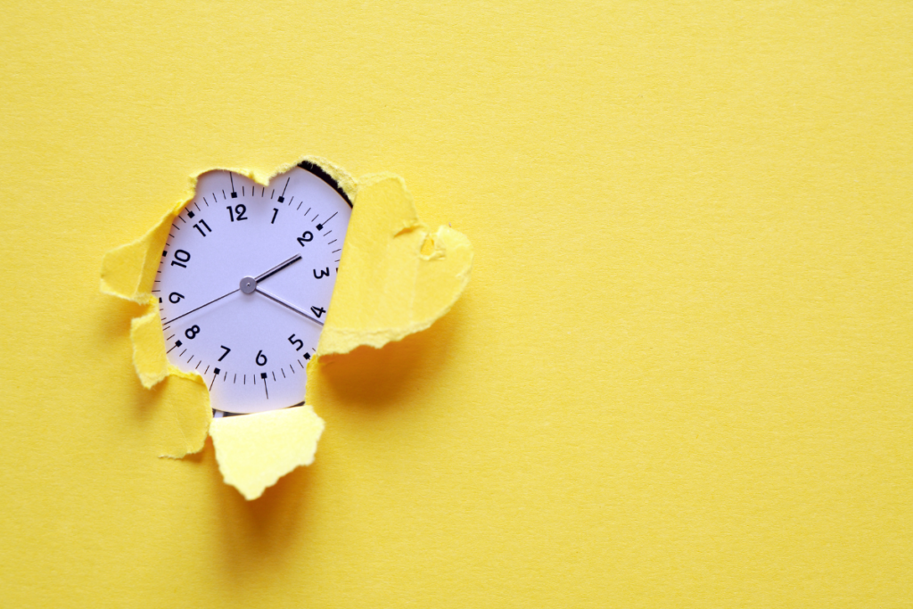 Meu tempo é precioso: como assumir o controle da sua rotina e parar de viver no automático Relógio analógico com ponteiros visíveis, parcialmente encoberto por papel amarelo rasgado. Fundo totalmente amarelo. Imagem representa o conceito de tempo.